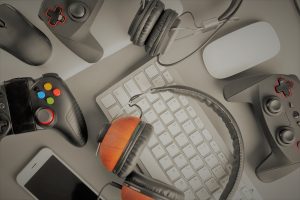Multiple game controllers, a mouse, a keyboard, a phone and a headset on a table.